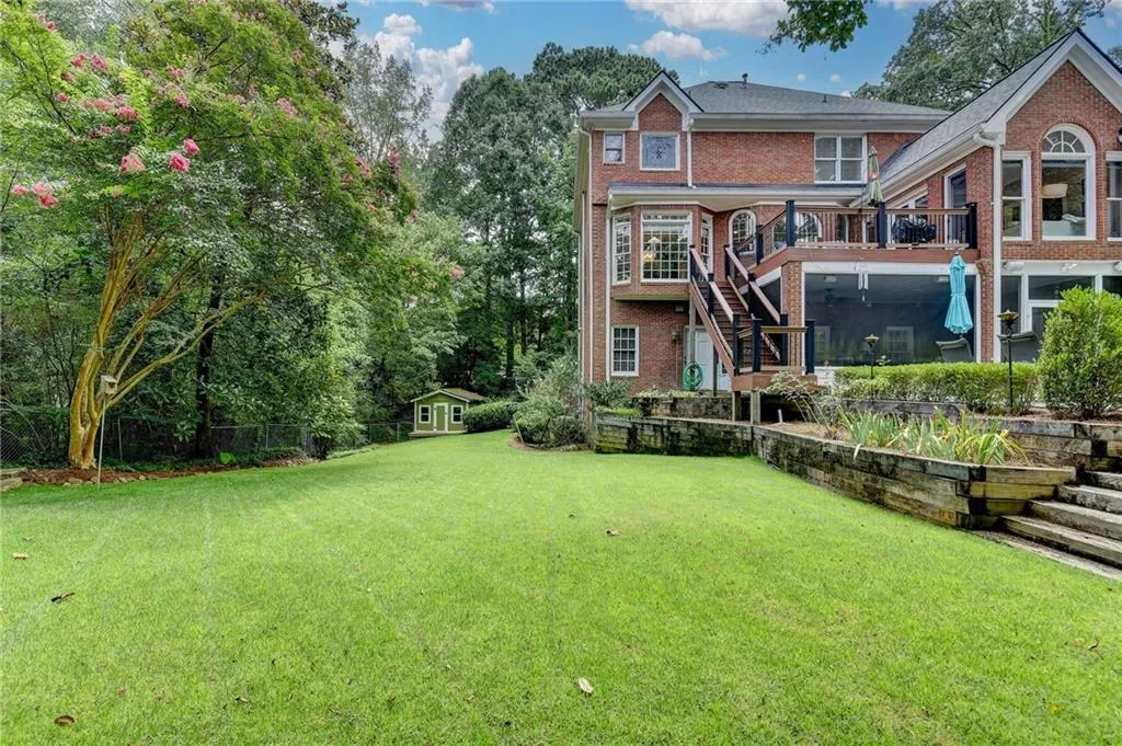 Rear view of house featuring stairs, brick siding, a wooden deck, and a yard