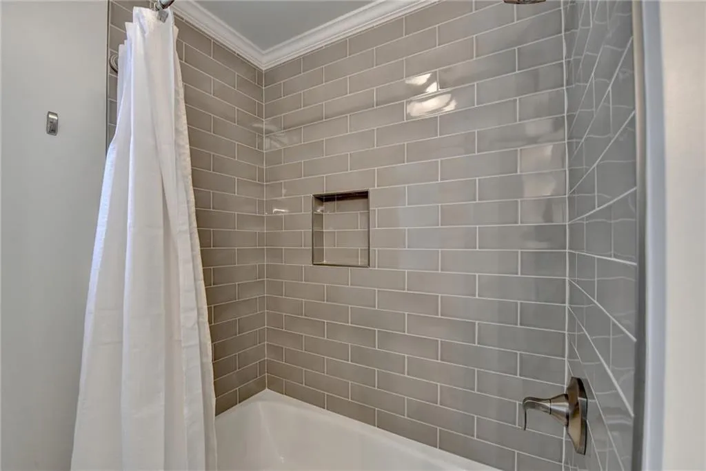 Bathroom with shower / bath combination with curtain and crown molding