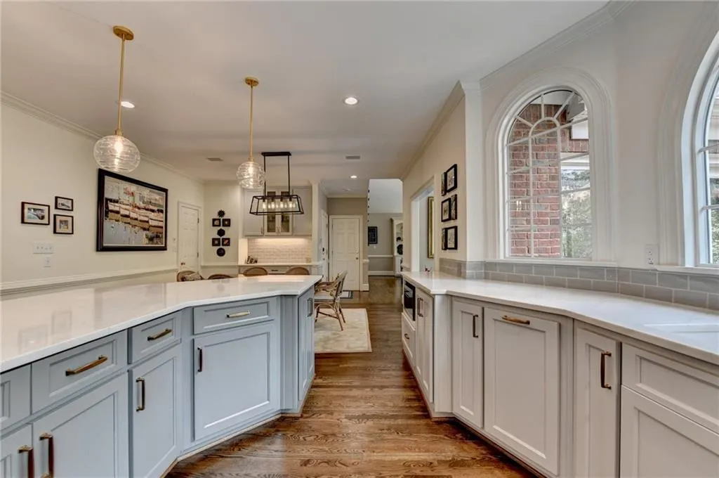 Kitchen with backsplash, ornamental molding, light wood-style floors, recessed lighting, and pendant lighting