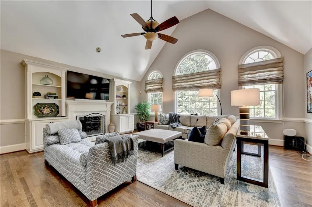 Living area with high vaulted ceiling, wood finished floors, a fireplace, and a ceiling fan