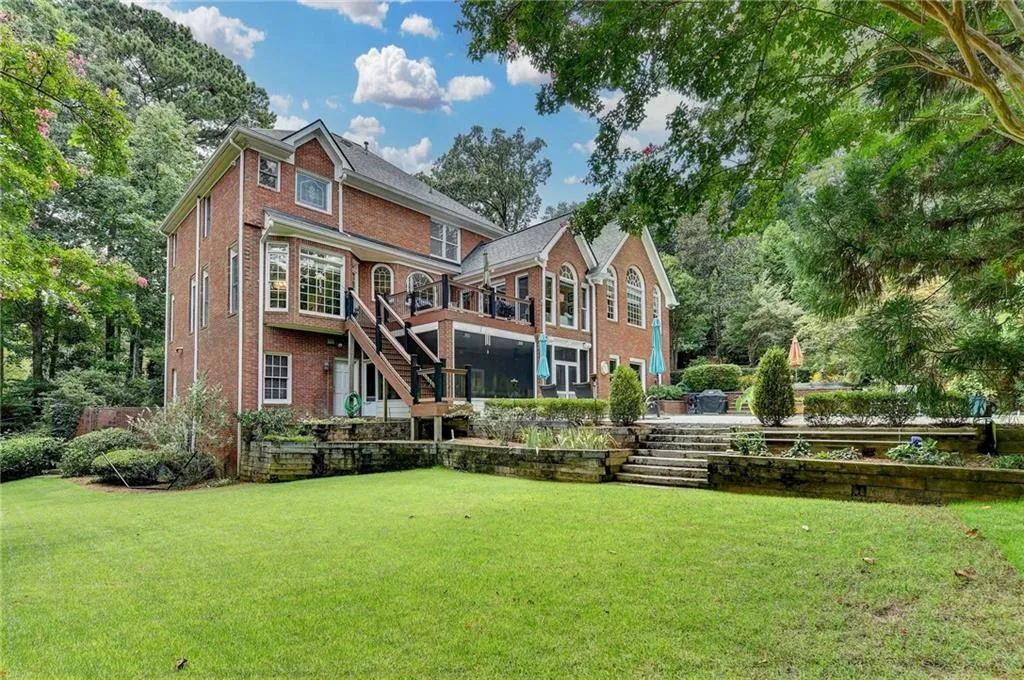 Back of house with stairs, a lawn, and brick siding