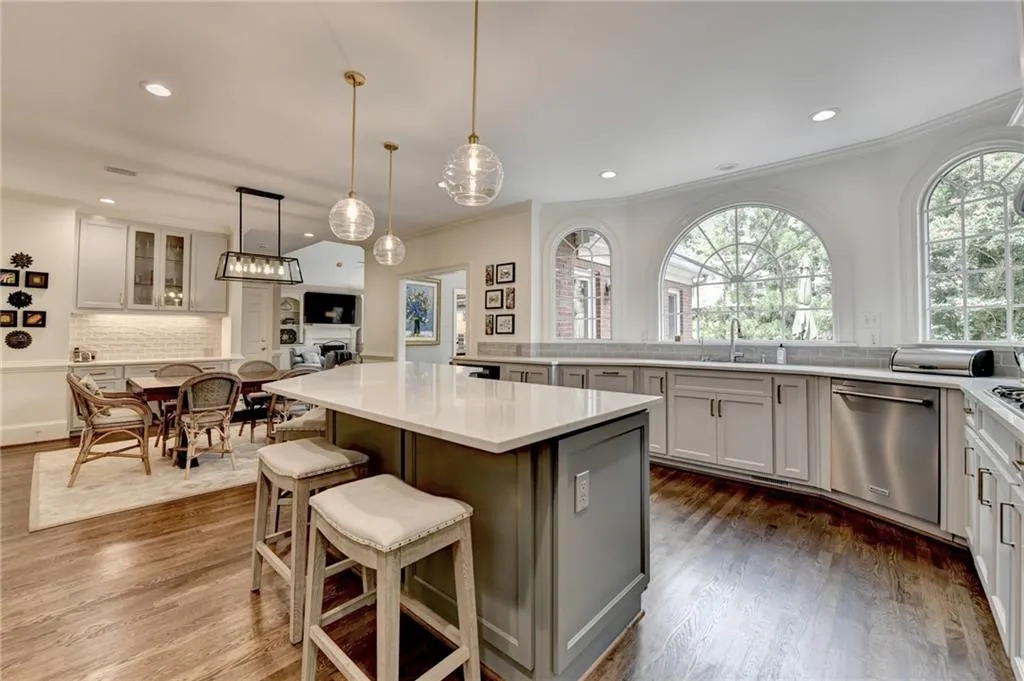 Kitchen with a breakfast bar, decorative backsplash, dark wood finished floors, stainless steel dishwasher, and crown molding