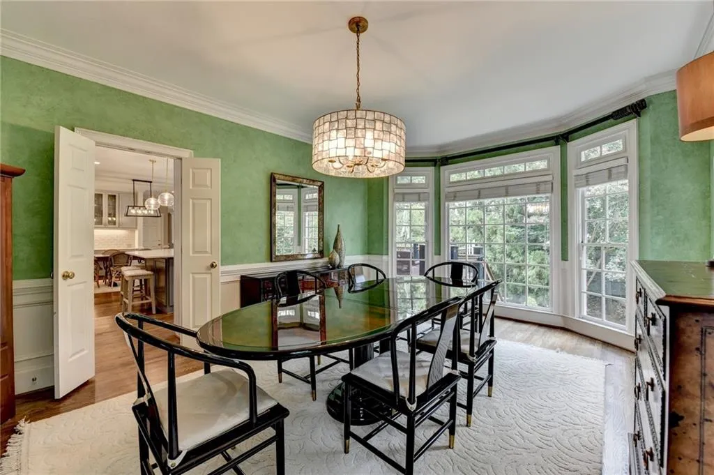 Dining space with a chandelier, wood finished floors, healthy amount of natural light, ornamental molding, and wainscoting