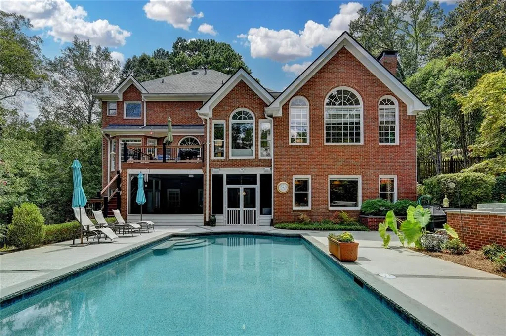 Rear view of house with a patio area, a sunroom, stairway, and brick siding