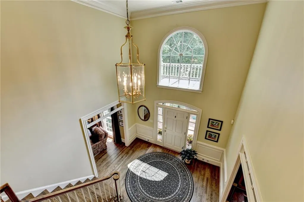 Entrance foyer featuring a chandelier, ornamental molding, wood finished floors, and a high ceiling