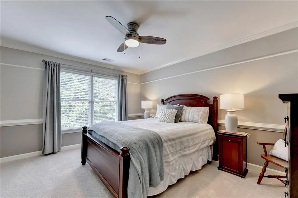 Bedroom featuring light carpet, ornamental molding, and a ceiling fan
