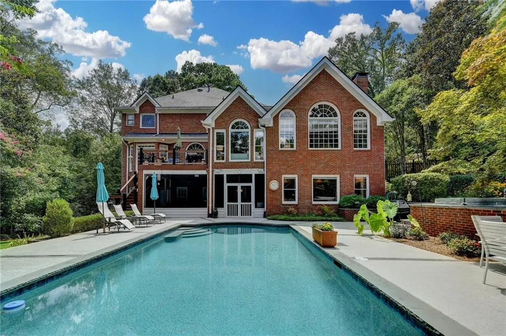 Back of house with a patio area, a chimney, an outdoor pool, and brick siding