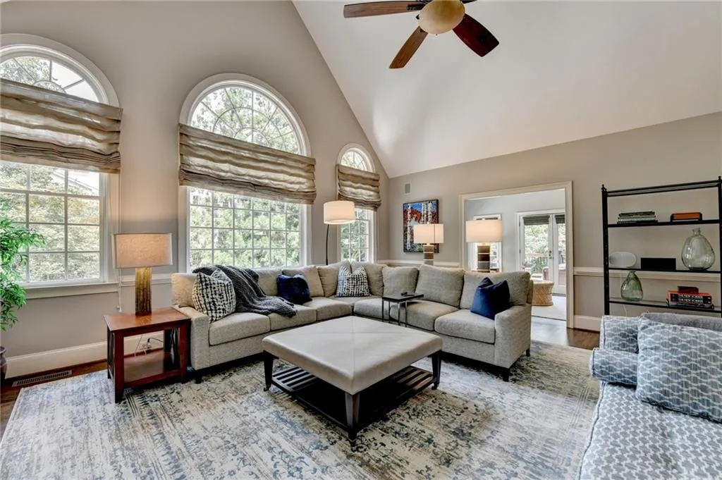 Living area with high vaulted ceiling, wood finished floors, and a ceiling fan