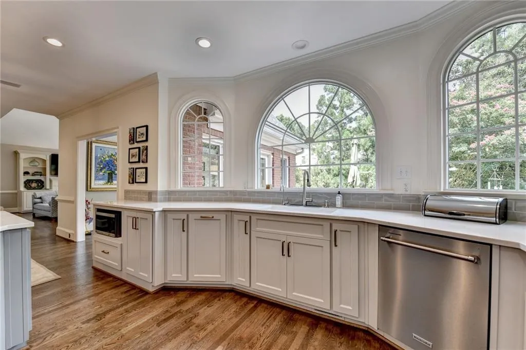 Kitchen featuring ornamental molding, stainless steel appliances, light wood finished floors, recessed lighting, and light stone counters