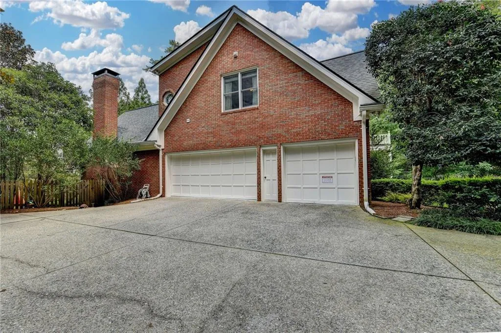 View of property exterior featuring brick siding, concrete driveway, a chimney, a garage, and a shingled roof