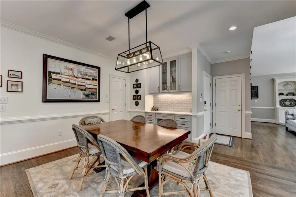 Dining area featuring dark wood-style floors, ornamental molding, and recessed lighting