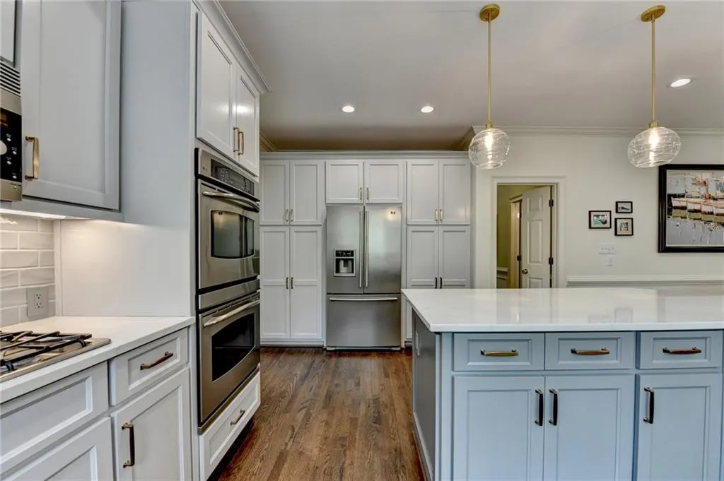 Kitchen featuring stainless steel appliances, white cabinets, decorative backsplash, hanging light fixtures, and recessed lighting