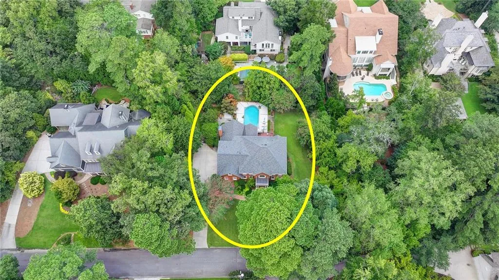 Aerial view of property and surrounding area featuring nearby suburban area and a pool