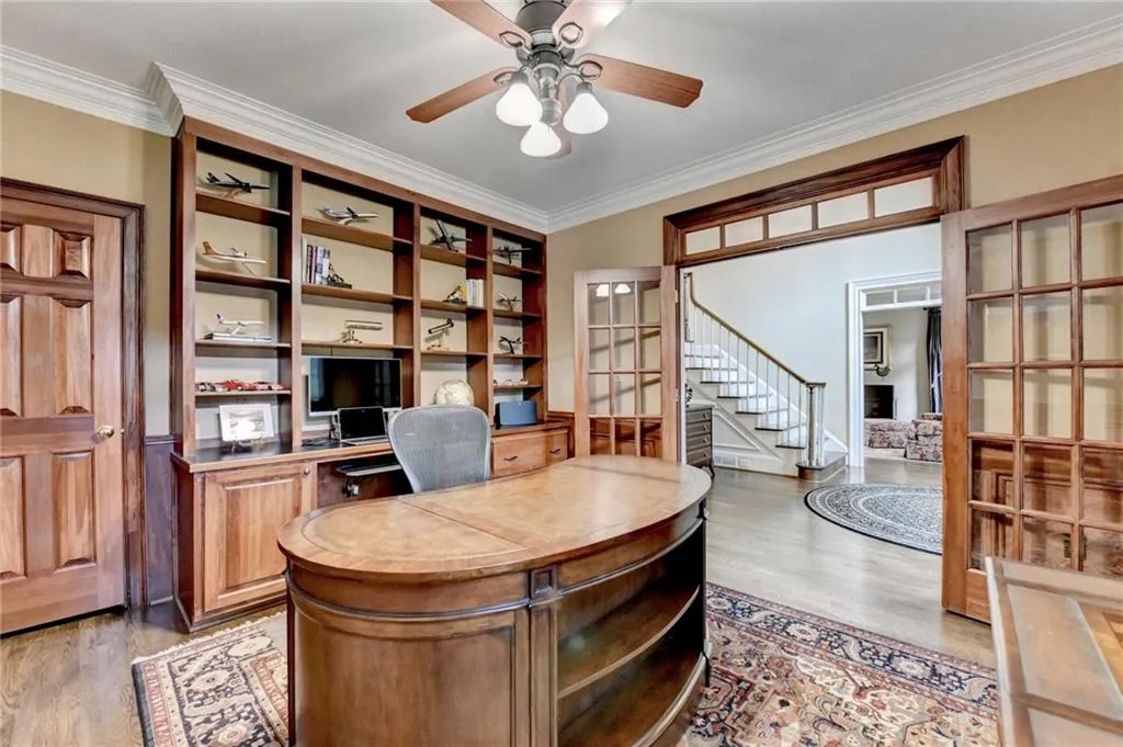 Office area featuring ornamental molding, light wood finished floors, and a ceiling fan