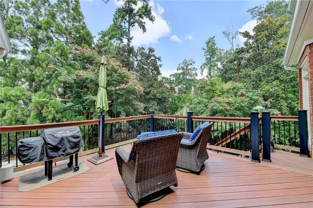 Wooden deck with view of scattered trees and a grill