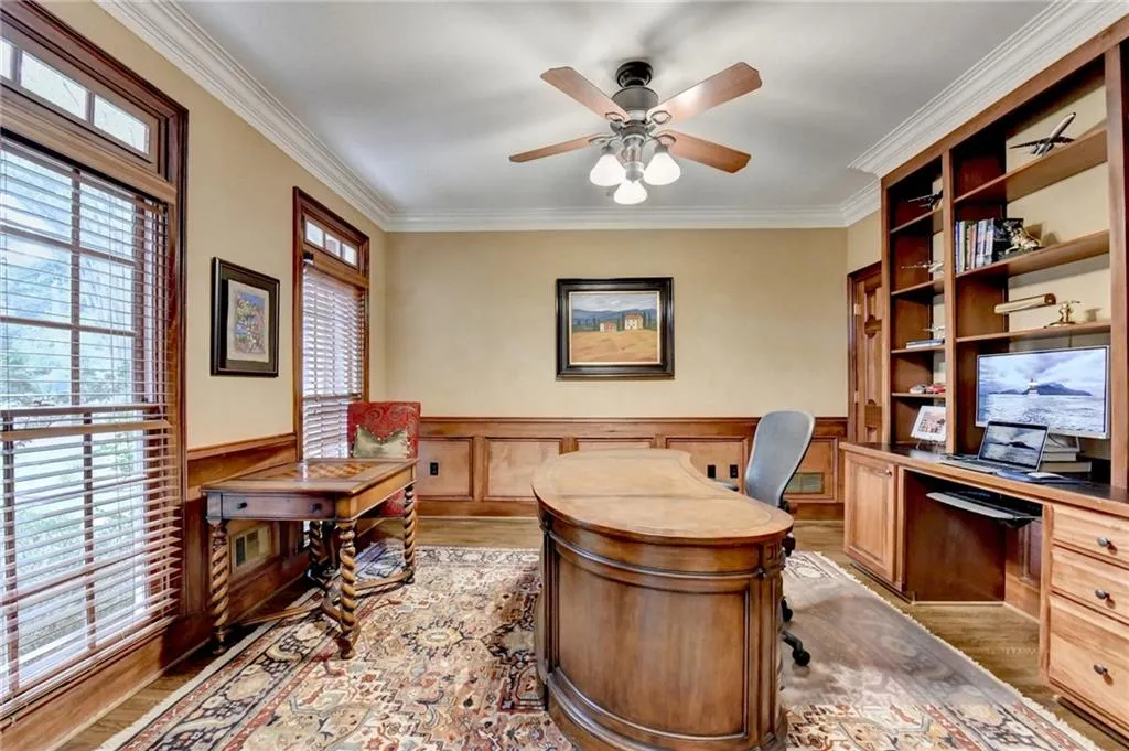 Office area featuring wainscoting, ornamental molding, light wood-style floors, ceiling fan, and a decorative wall