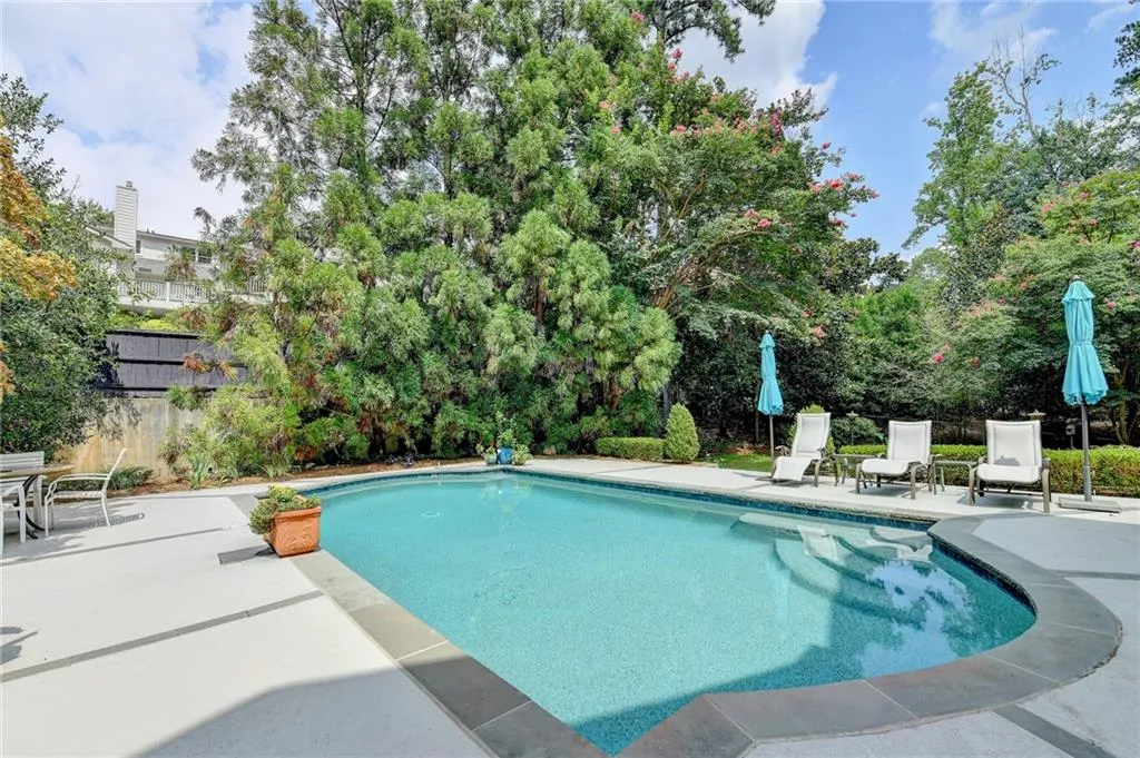 Swimming pool with a patio and view of wooded area