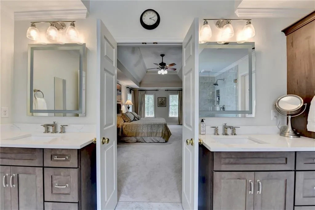 Ensuite bathroom with ornamental molding, a stall shower, two vanities, and a ceiling fan