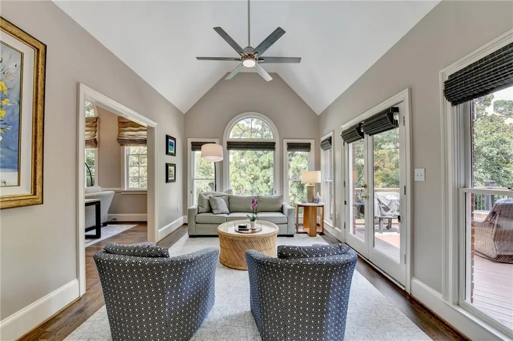 Sunroom / solarium with wood finished floors, healthy amount of natural light, high vaulted ceiling, and french doors
