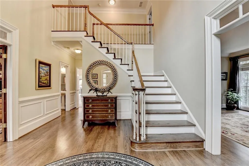Staircase featuring crown molding, wood finished floors, and a towering ceiling