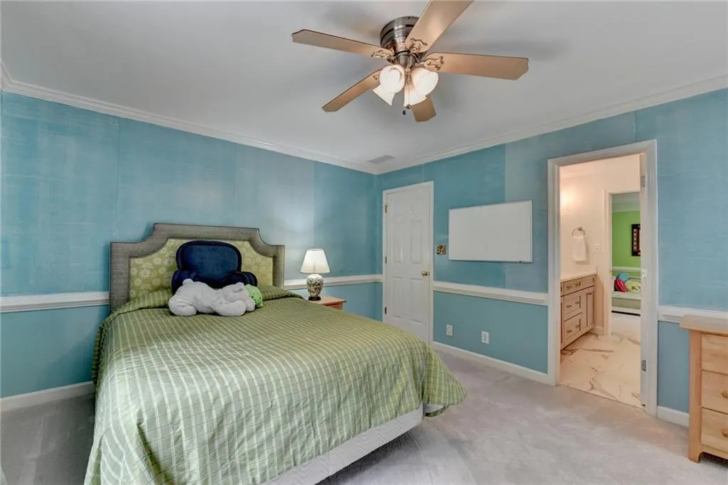 Carpeted bedroom featuring crown molding, a ceiling fan, and ensuite bathroom