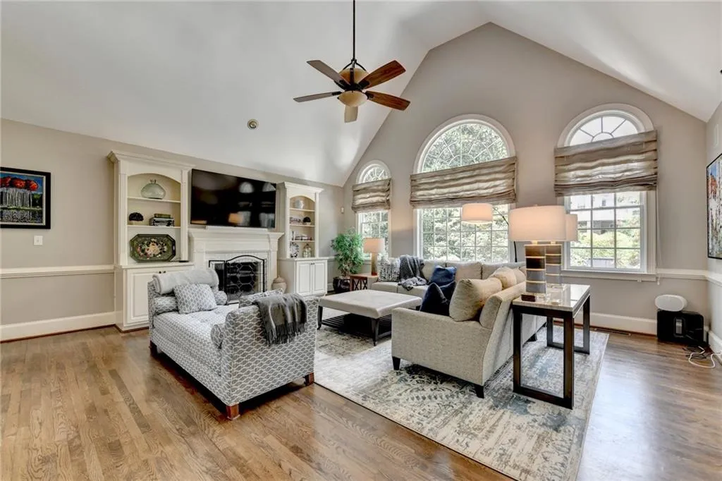 Living room featuring high vaulted ceiling, a fireplace, light wood finished floors, and ceiling fan