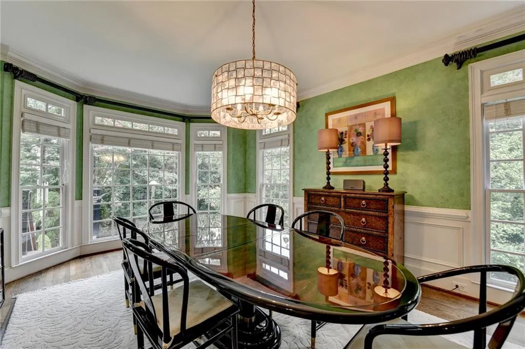 Dining space with light wood-style floors, a chandelier, wainscoting, crown molding, and a decorative wall