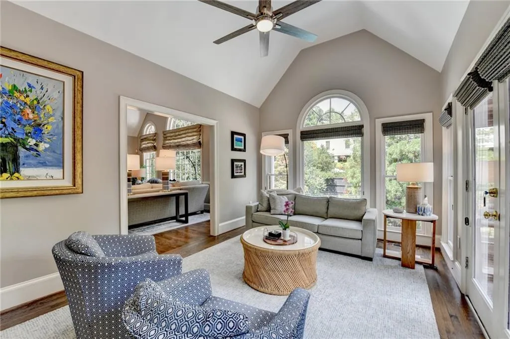 Living area with healthy amount of natural light, wood finished floors, high vaulted ceiling, and a ceiling fan