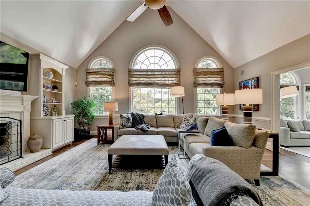 Living area with high vaulted ceiling, a fireplace, a ceiling fan, and wood finished floors