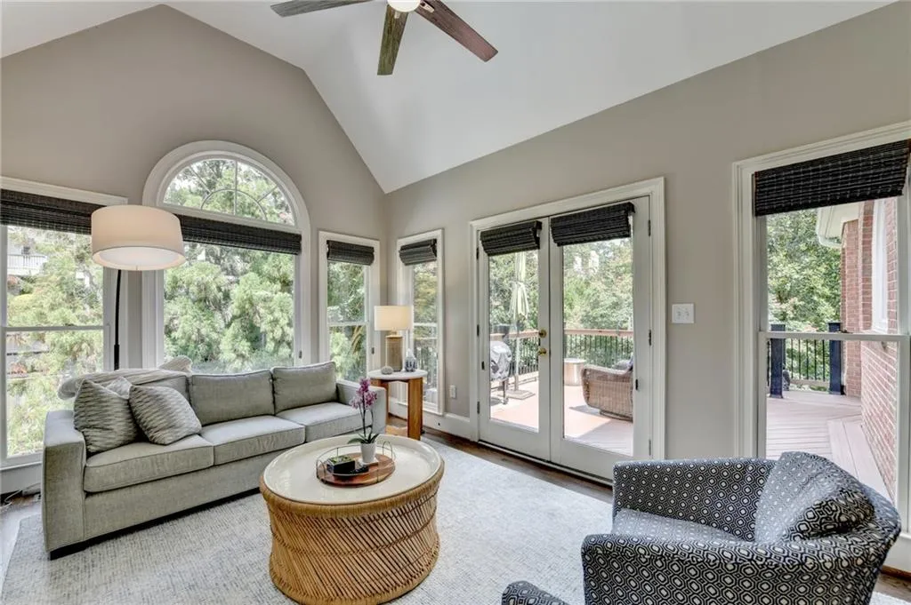 Living area featuring wood finished floors, healthy amount of natural light, high vaulted ceiling, french doors, and ceiling fan