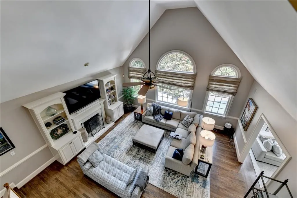 Living area with high vaulted ceiling, a fireplace, wood finished floors, ceiling fan, and healthy amount of natural light