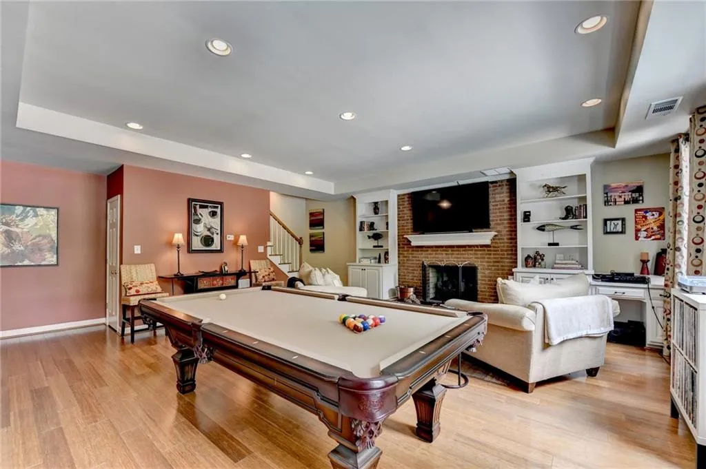 Game room with billiards table, a tray ceiling, a fireplace, recessed lighting, and light wood-type flooring
