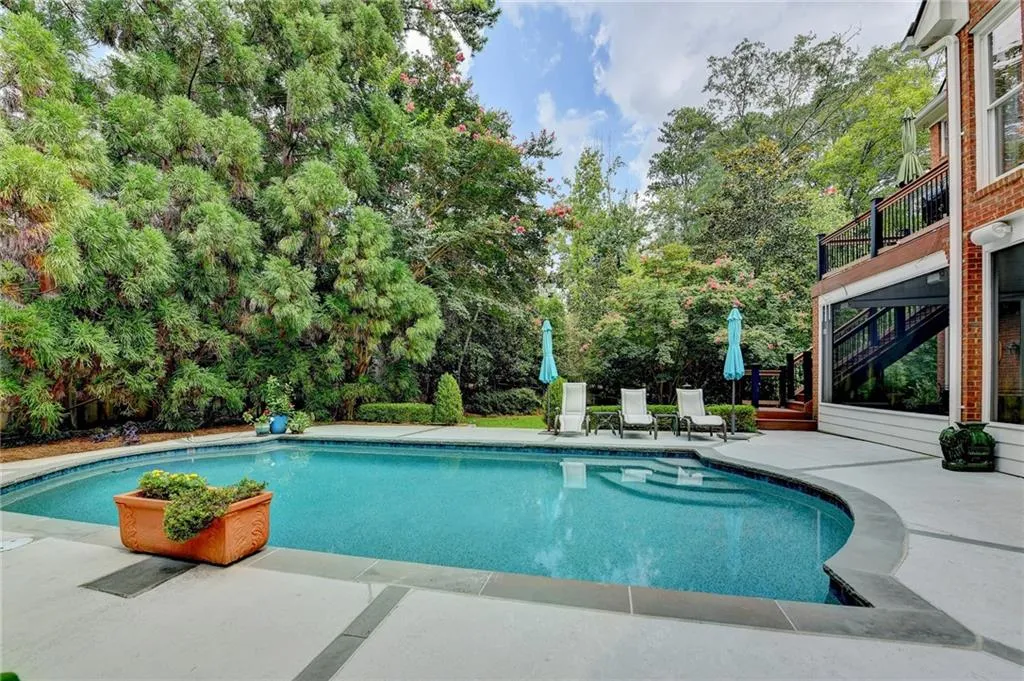 Swimming pool featuring a patio area, view of wooded area, stairs, and a balcony