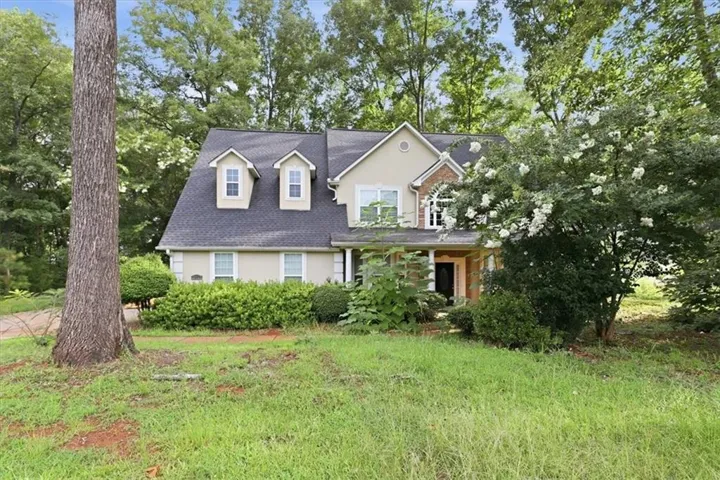 Two-story residence featuring a gray shingle roof and dormer windows