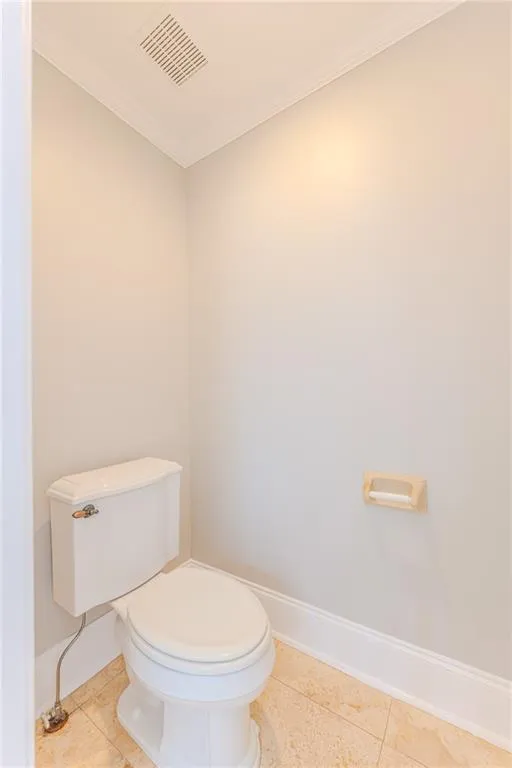 Half bathroom featuring crown molding and light tile patterned floors