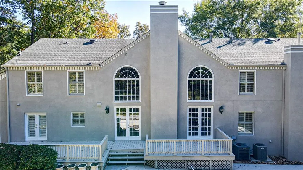 Back of house featuring a chimney, a wooden deck, french doors, and stucco siding