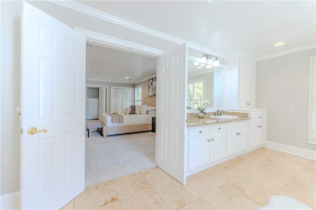 Ensuite bathroom with vanity, light colored carpet, crown molding, recessed lighting, and light tile patterned flooring