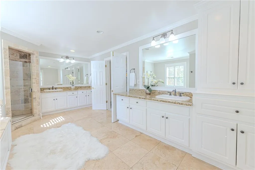 Bathroom with two vanities, ornamental molding, a stall shower, light tile patterned flooring, and recessed lighting