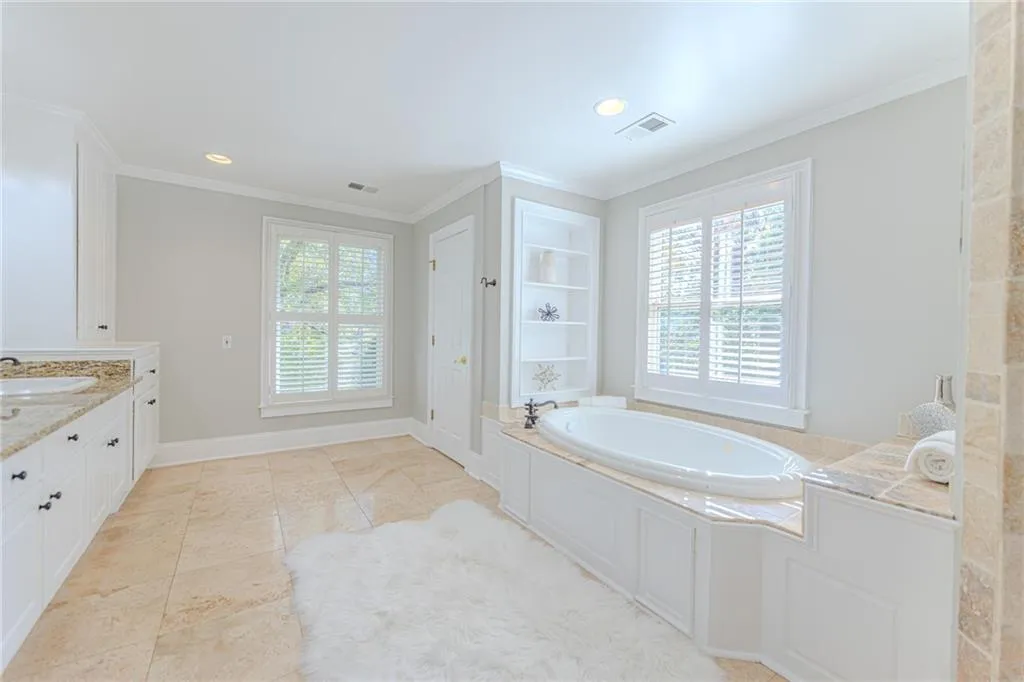 Bathroom with crown molding, a garden tub, healthy amount of natural light, vanity, and recessed lighting