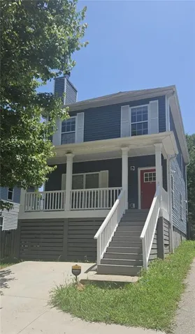 Two-story residence featuring a covered front porch with white railings, a red front door, and blue siding