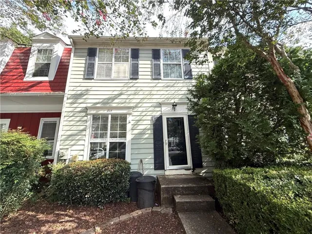 Siding exterior with black shutters, mature landscaping, and a concrete pathway leading to the entry