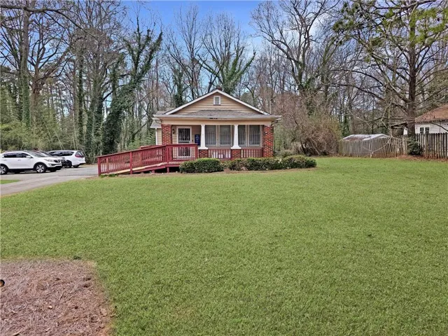 View of front facade with brick siding, a porch, a front yard, and fence