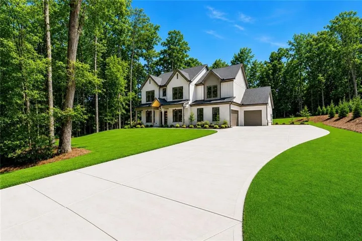 Contemporary exterior with a two-car garage, expansive concrete driveway, and a lush green lawn