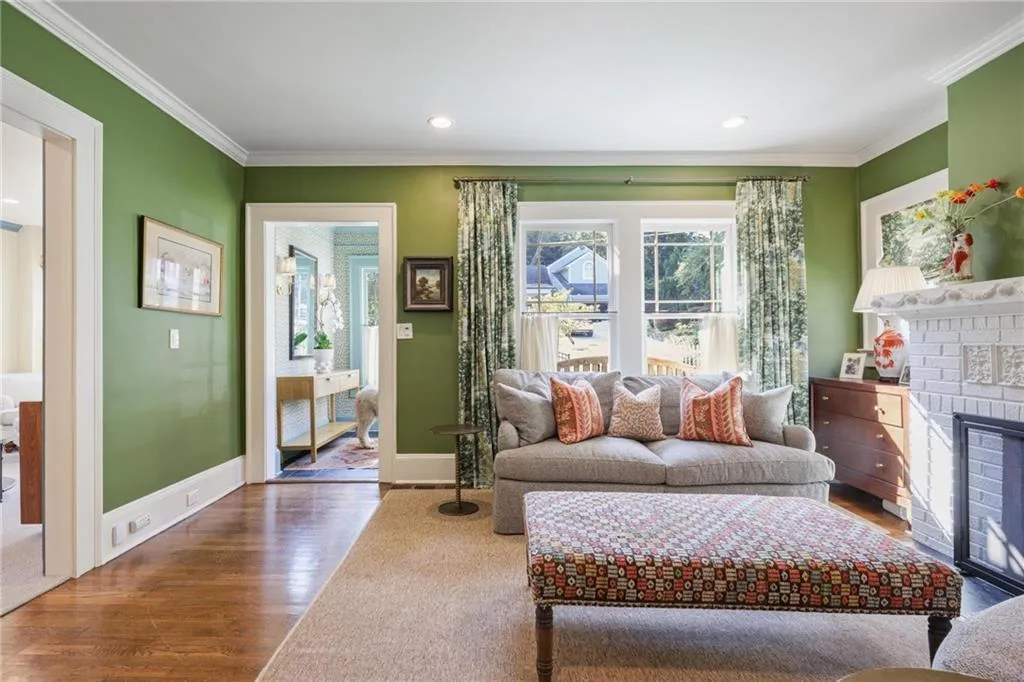 Living room featuring ornamental molding, wood finished floors, a brick fireplace, and recessed lighting