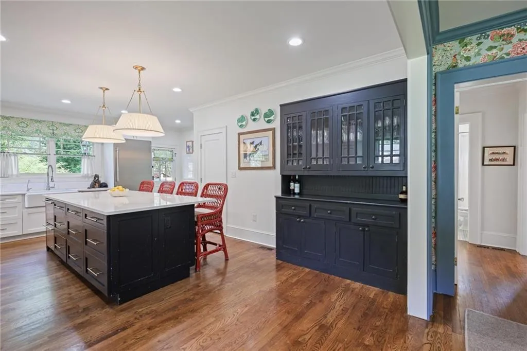 Kitchen featuring dark cabinets, a breakfast bar area, crown molding, decorative light fixtures, and dark wood finished floors