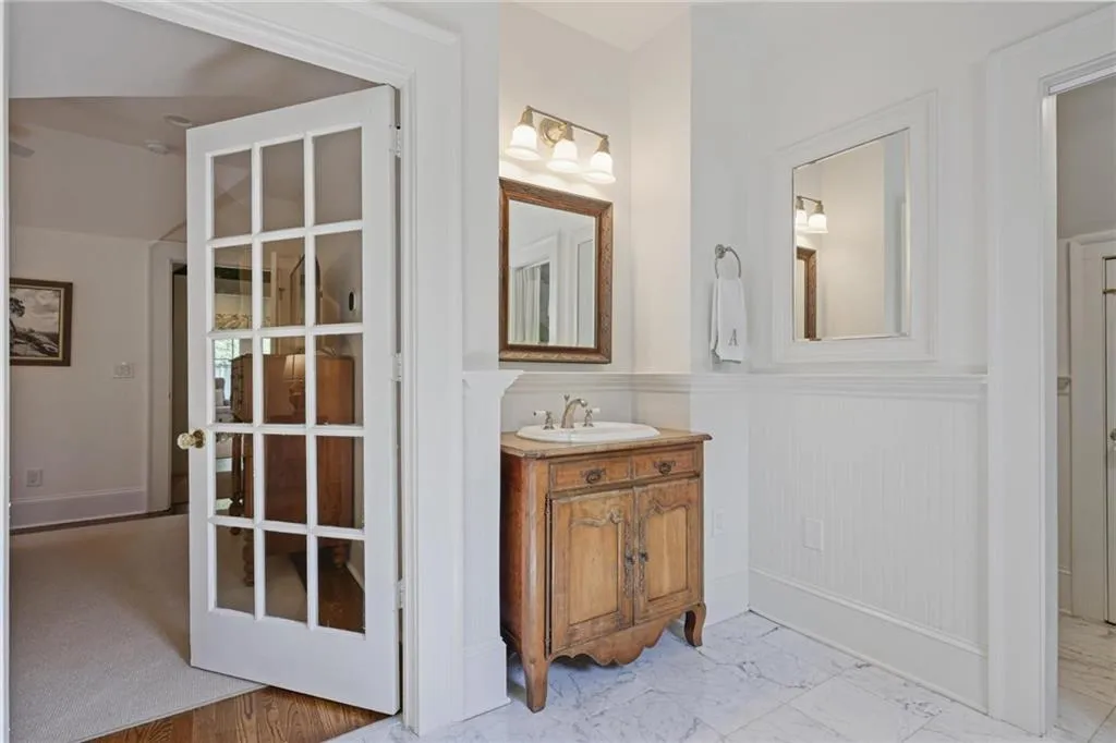 Bathroom with vanity, a wainscoted wall, and light marble finish flooring