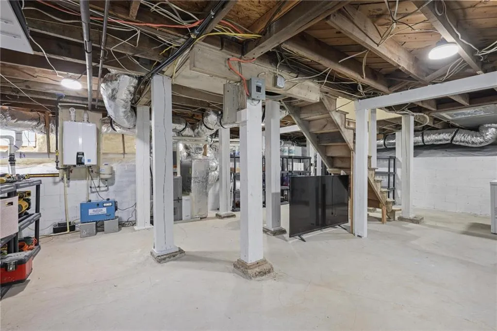 Unfinished basement with stairs and tankless water heater