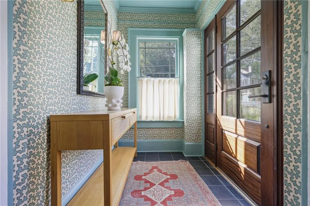 Entryway with wallpapered walls, healthy amount of natural light, tile patterned floors, and crown molding