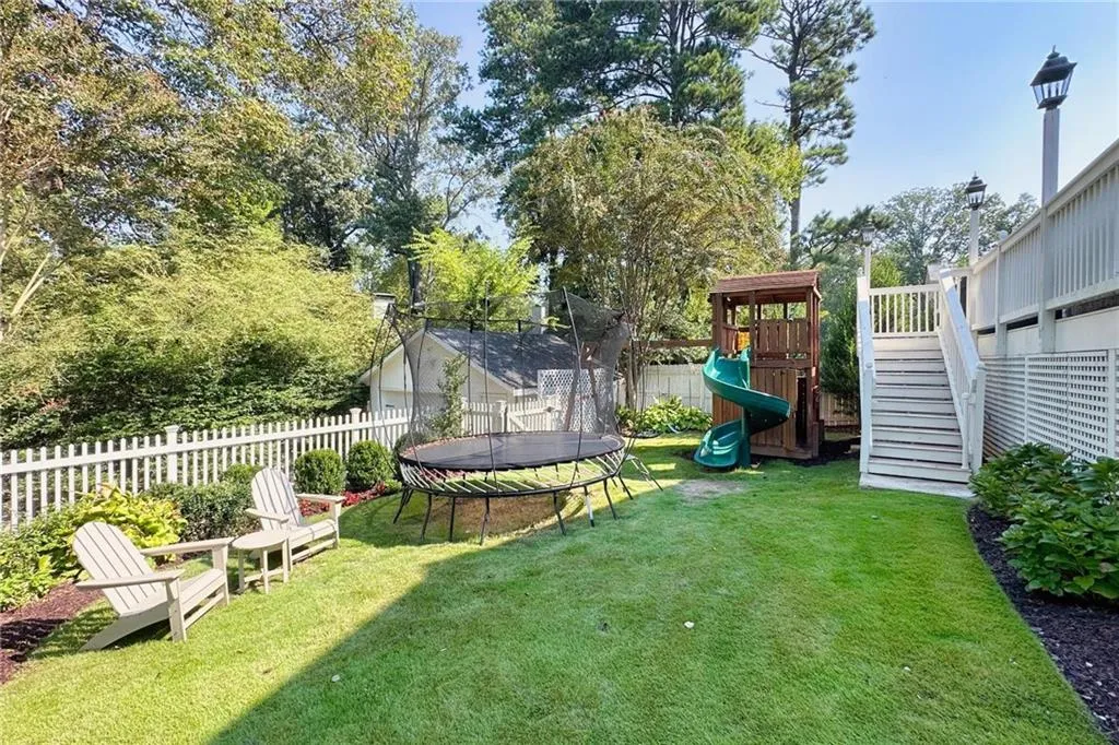 Fenced backyard with a trampoline and a playground