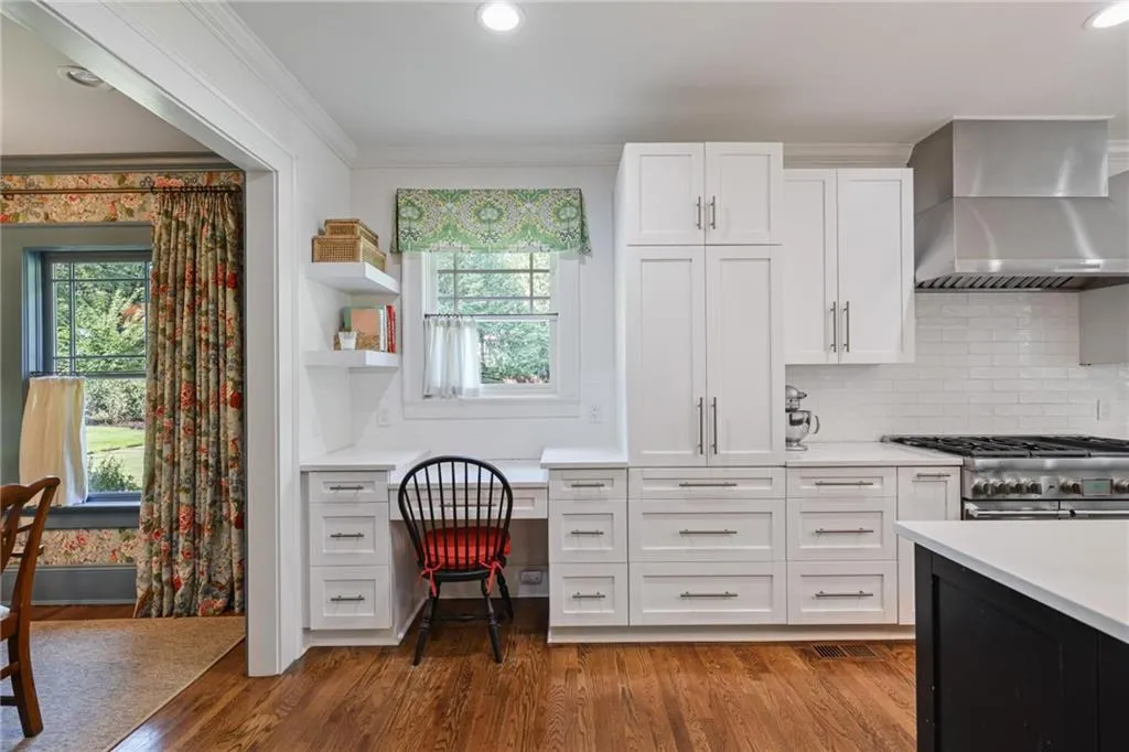 Kitchen featuring wall chimney range hood, white cabinets, open shelves, dark wood-style flooring, and decorative backsplash